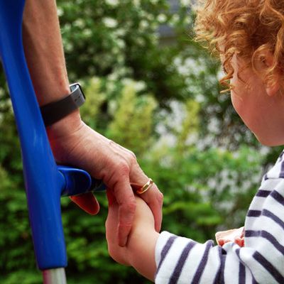 Neuaufnahme Frauenhand an Unterarmgehstütze mit Kinderhand, kleines Kind mit roten Locken im Anschnitt (Mutter und Sohn).