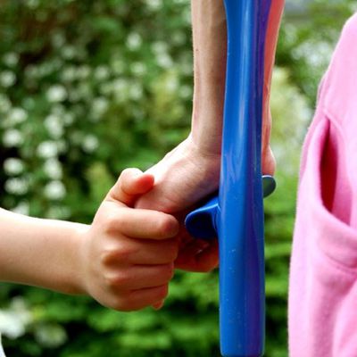 Nahaufnahme Unterarmgehstütze mit sich haltenden Händen von Mutter und Kind