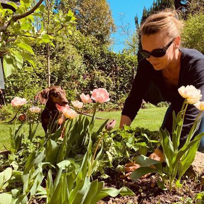 Gartenszene Sandra Olbrich, auf allen Vieren, beim Unkraut jäten mit Dackel Ida, der interessiert zuschaut